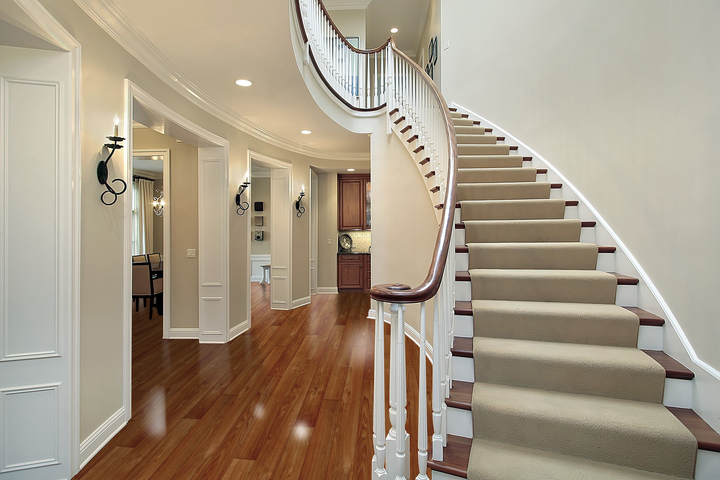 traditional curved staircase with hardwood floors and beige carpet runner